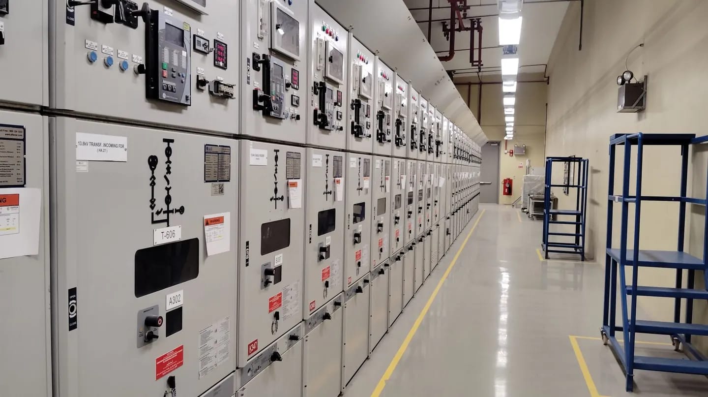Medium-voltage switchgear lineup with protection relays and metering, receding down a clean facility aisle
