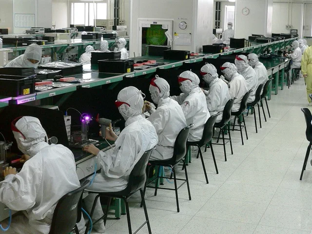 Quality control technicians inspecting electronics production lines in cleanroom attire